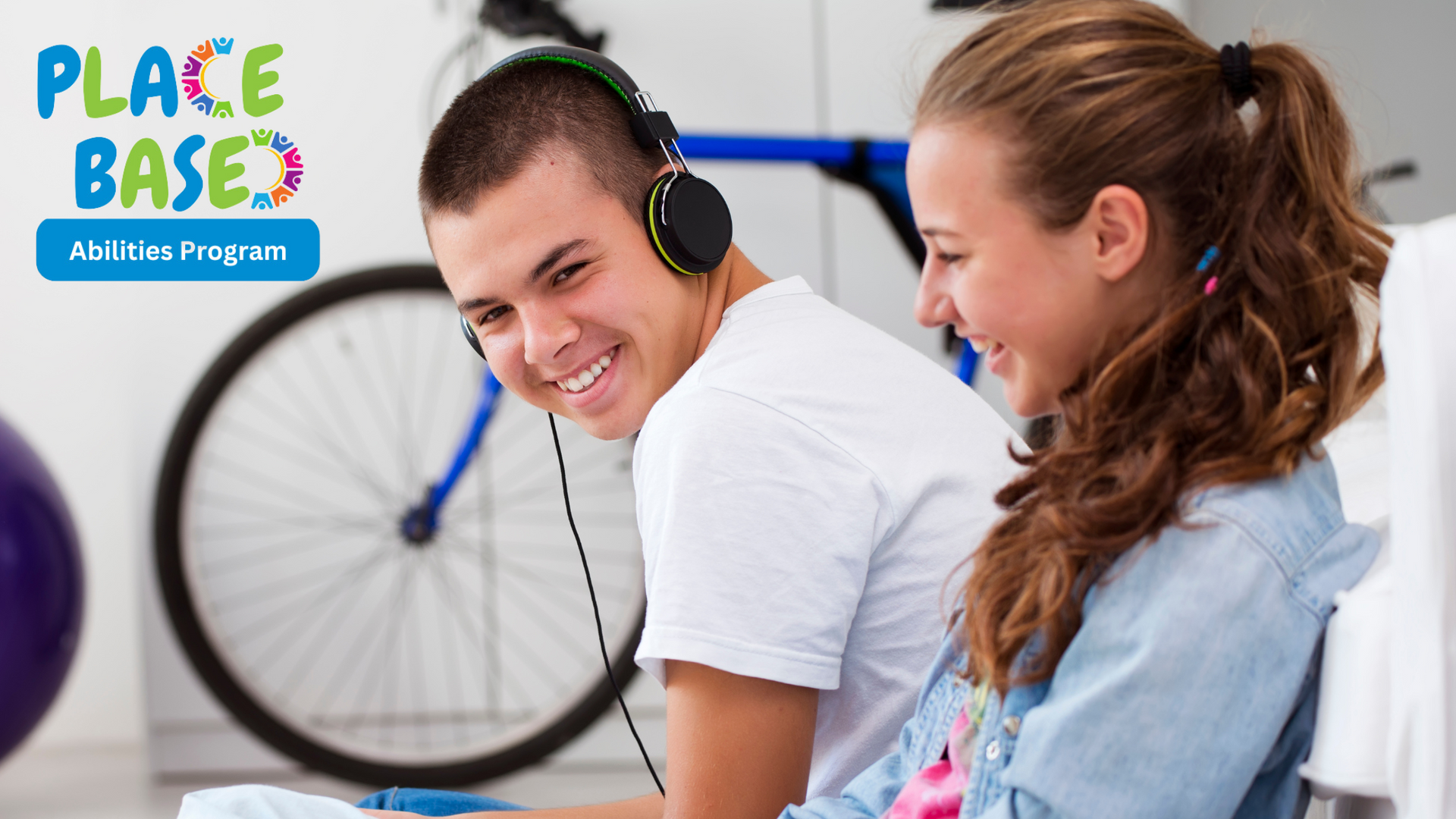 Two young people smiling and sitting next to each other 