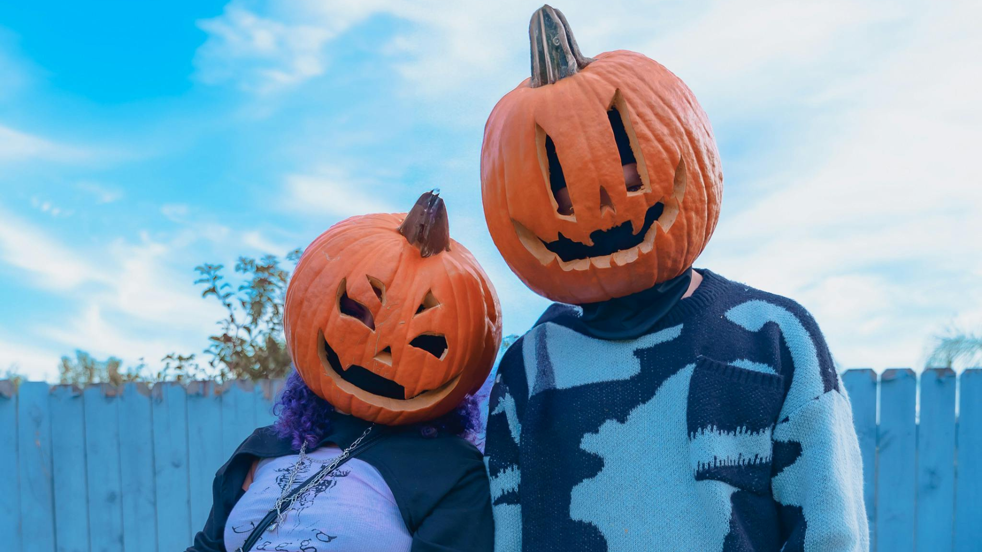Image of two young people wearing  halloween pumpkins on their heads
