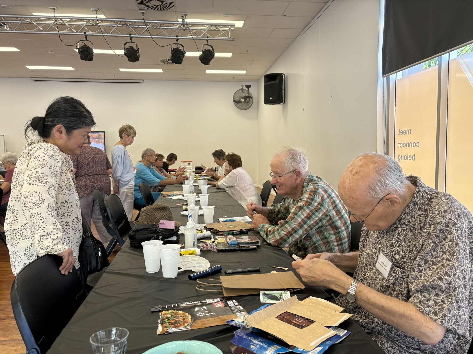 Seniors sitting at a long table doing art and crafts