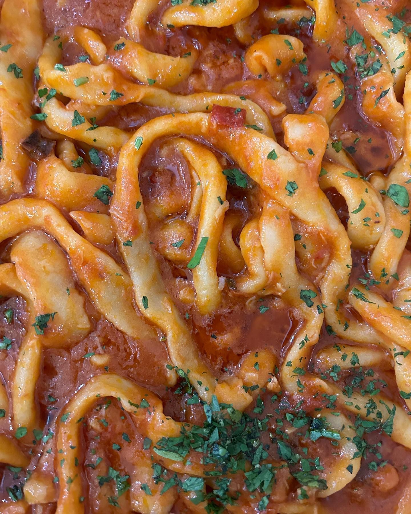 Pasta al sugo di pomodoro rosso, guarnita con prezzemolo.