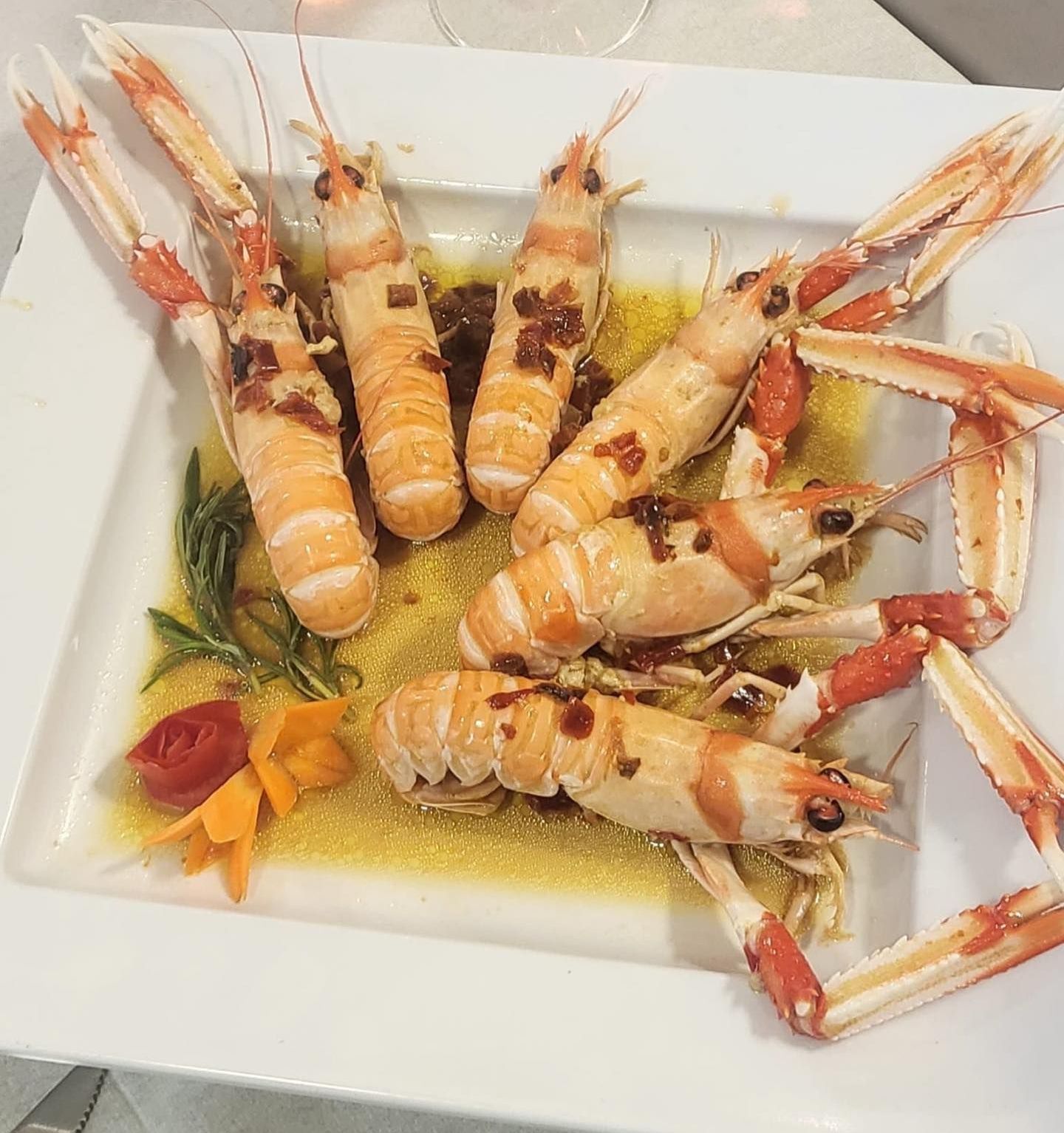 Piatto di scampi cotti su un piatto bianco, serviti con salsa e guarnizione.