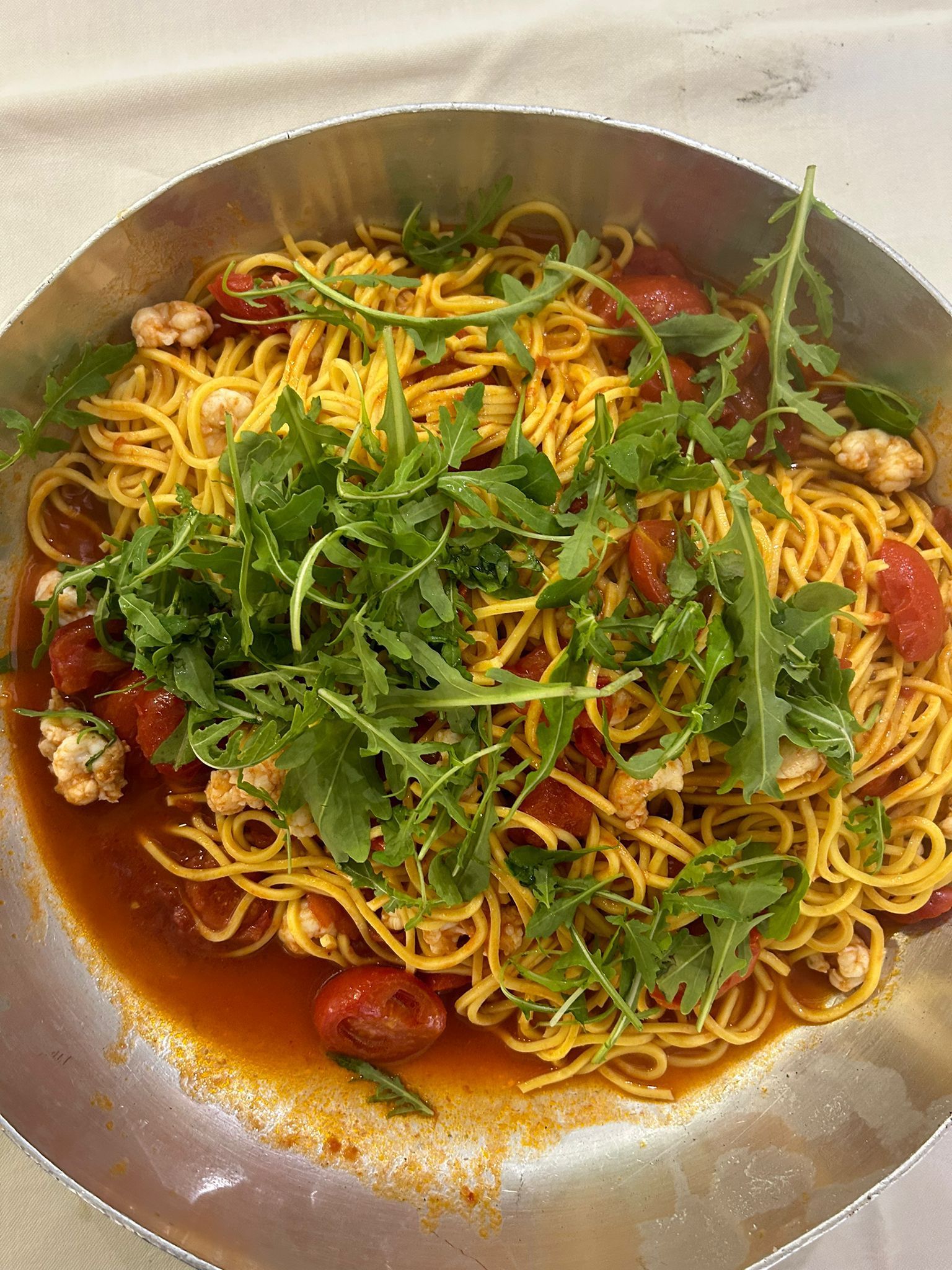 Piatto di spaghetti con pomodori e rucola in una padella d'argento.