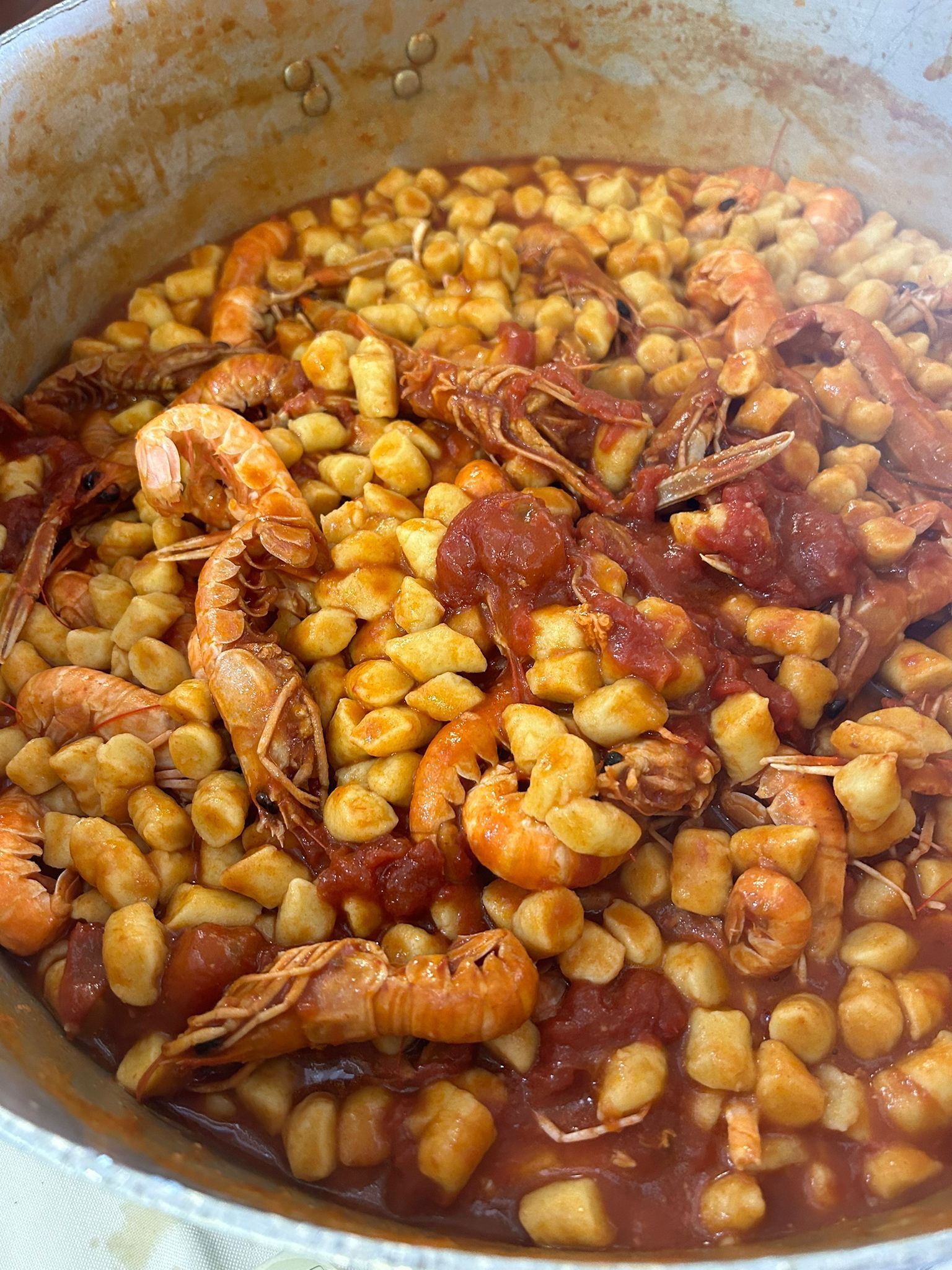 Pentola di gamberi e gnocchi in salsa di pomodoro rosso.