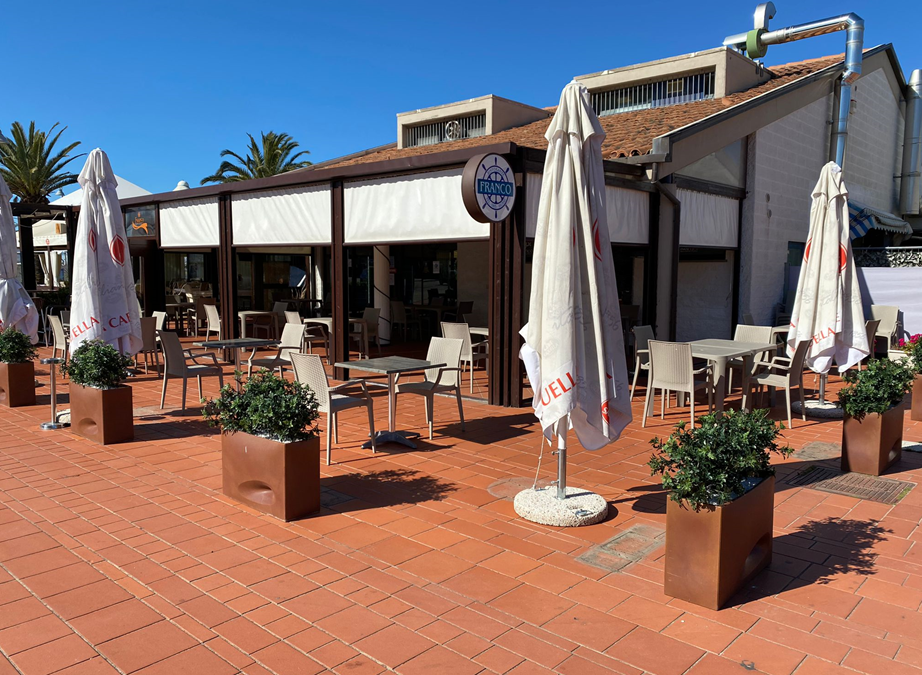 Un ristorante con tavoli, sedie e ombrelloni all'esterno