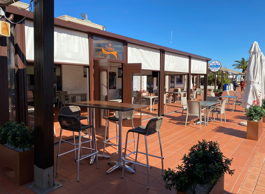 Un ristorante con tavoli e sedie all'esterno in una giornata di sole