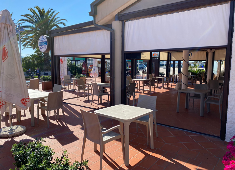 Un ristorante con tavoli, sedie e un ombrellone.