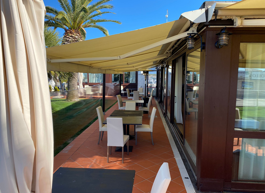 Un ristorante con tavoli e sedie sotto una tenda da sole