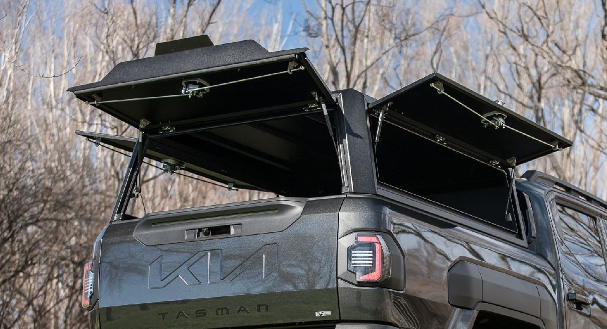 Kia Tasman with MAXIM Hard Lid and MAX Tie down rails in a park.