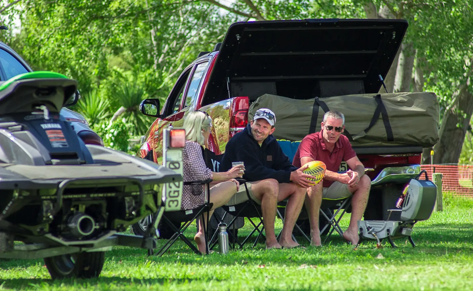 A group of people camping in front of a truck with a MAXIM Hard Lid open.