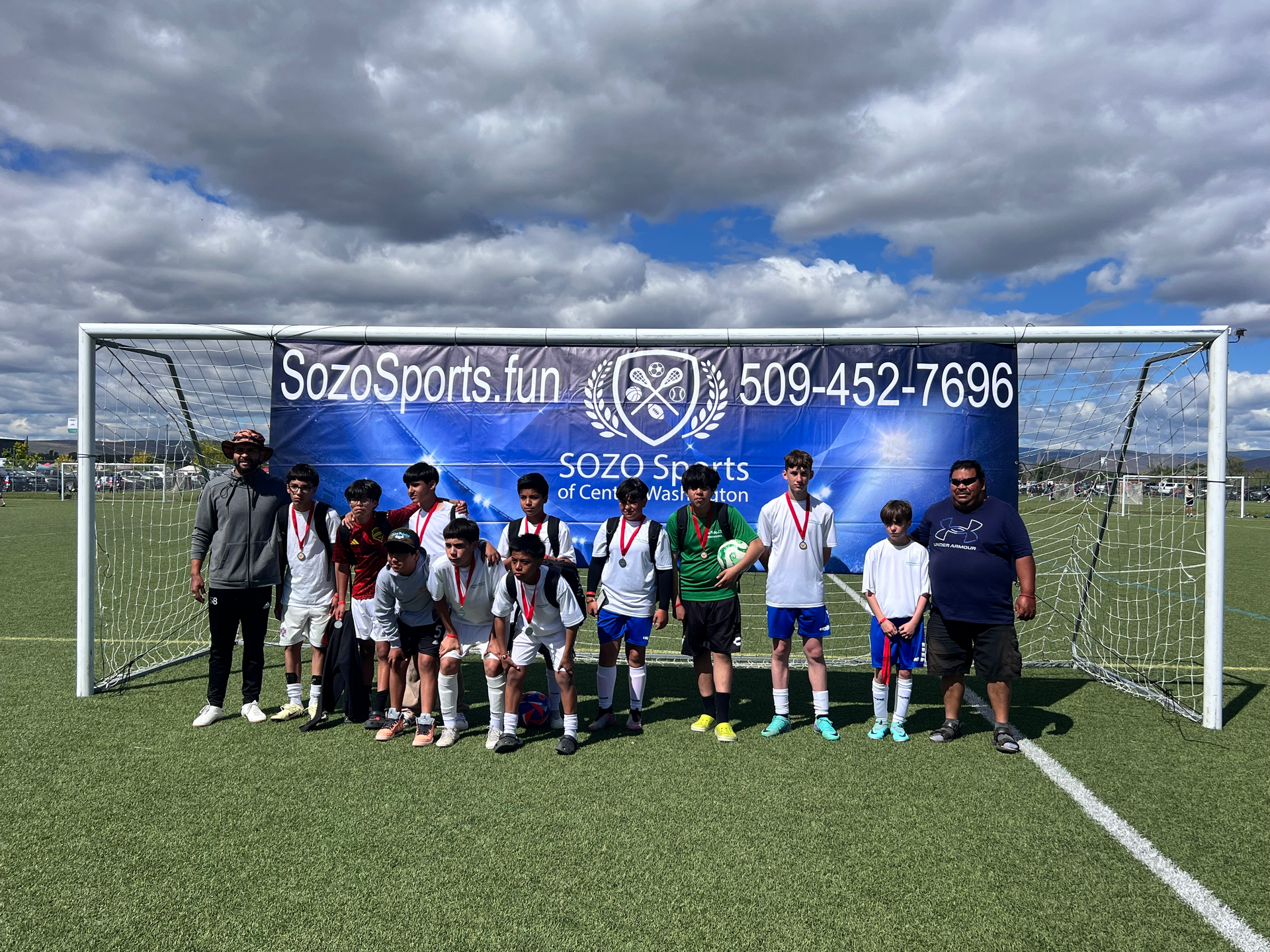 A group of young boys are posing for a picture on a soccer field.