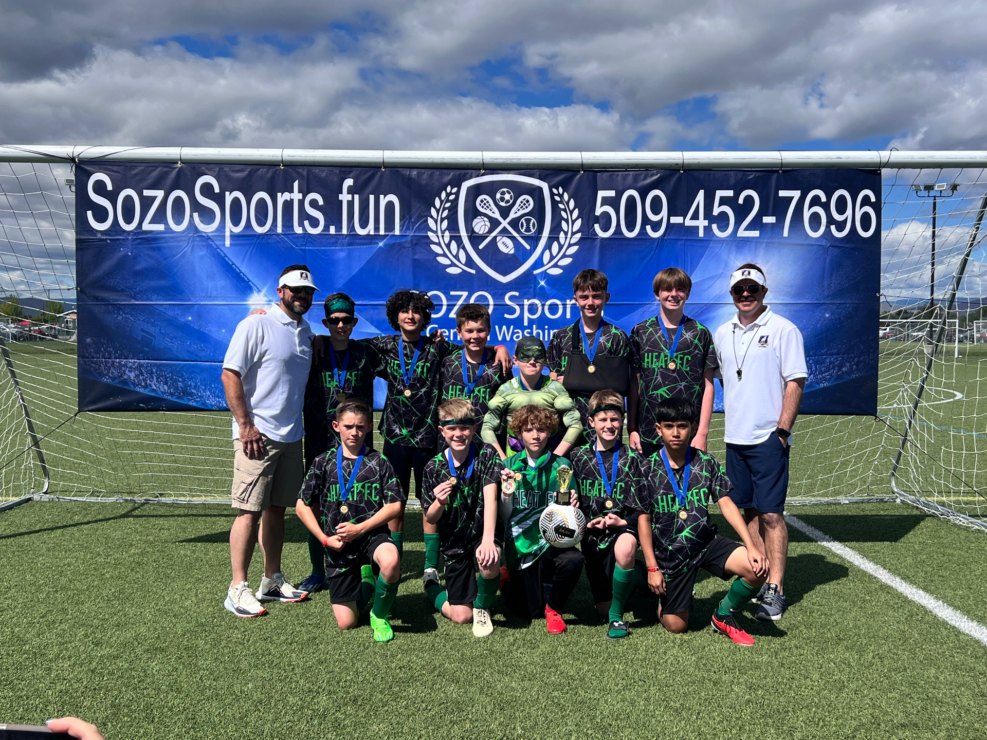 A group of young boys are posing for a picture on a soccer field.
