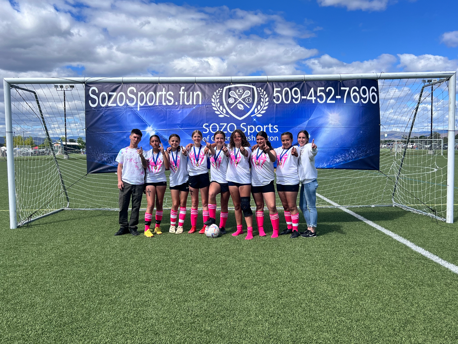 A group of people are posing for a picture on a soccer field.