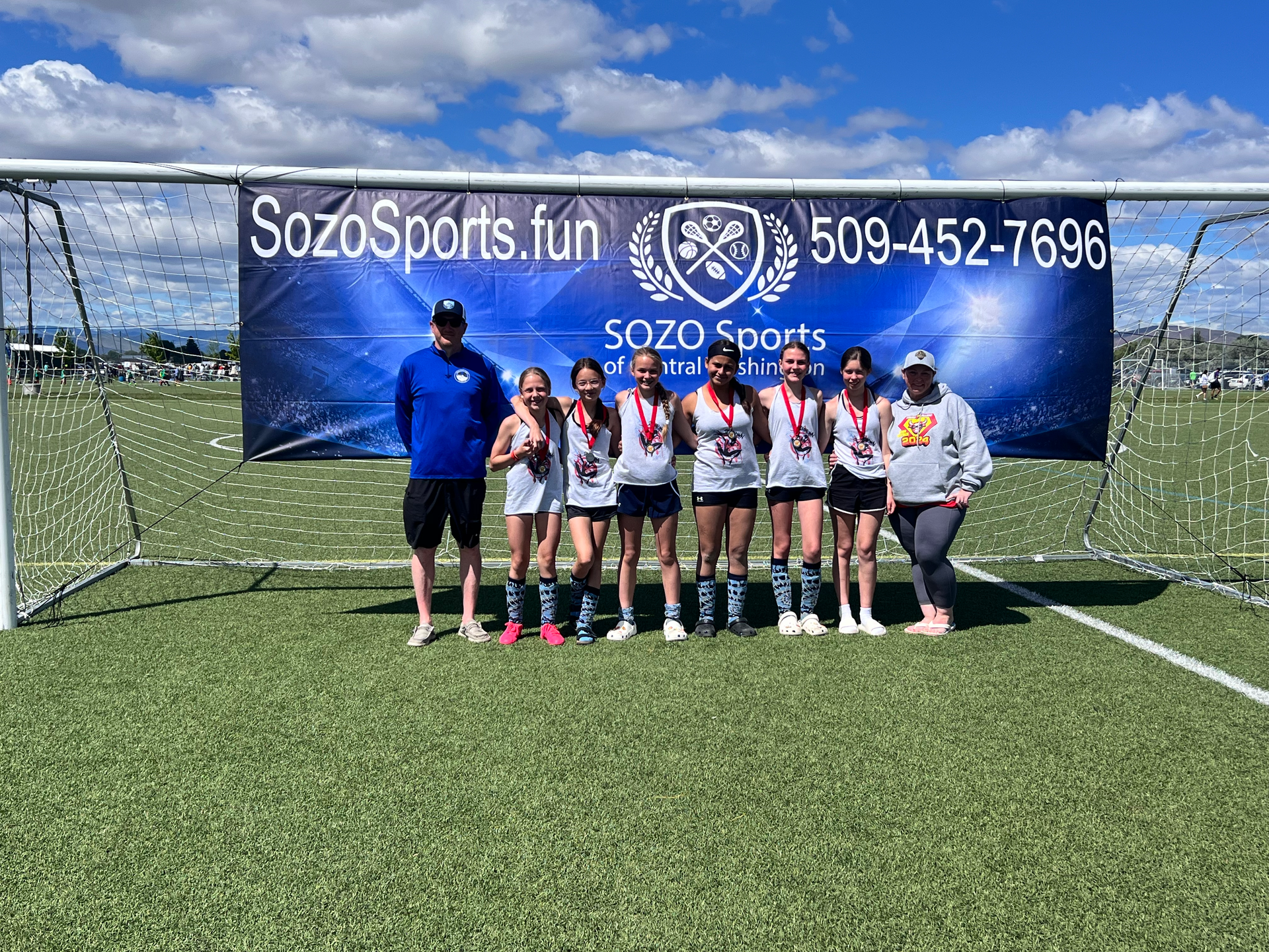 A group of girls are posing for a picture on a soccer field.