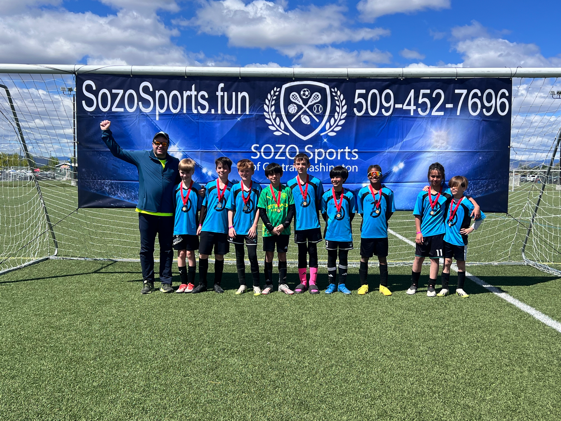 A group of young boys are posing for a picture on a soccer field.