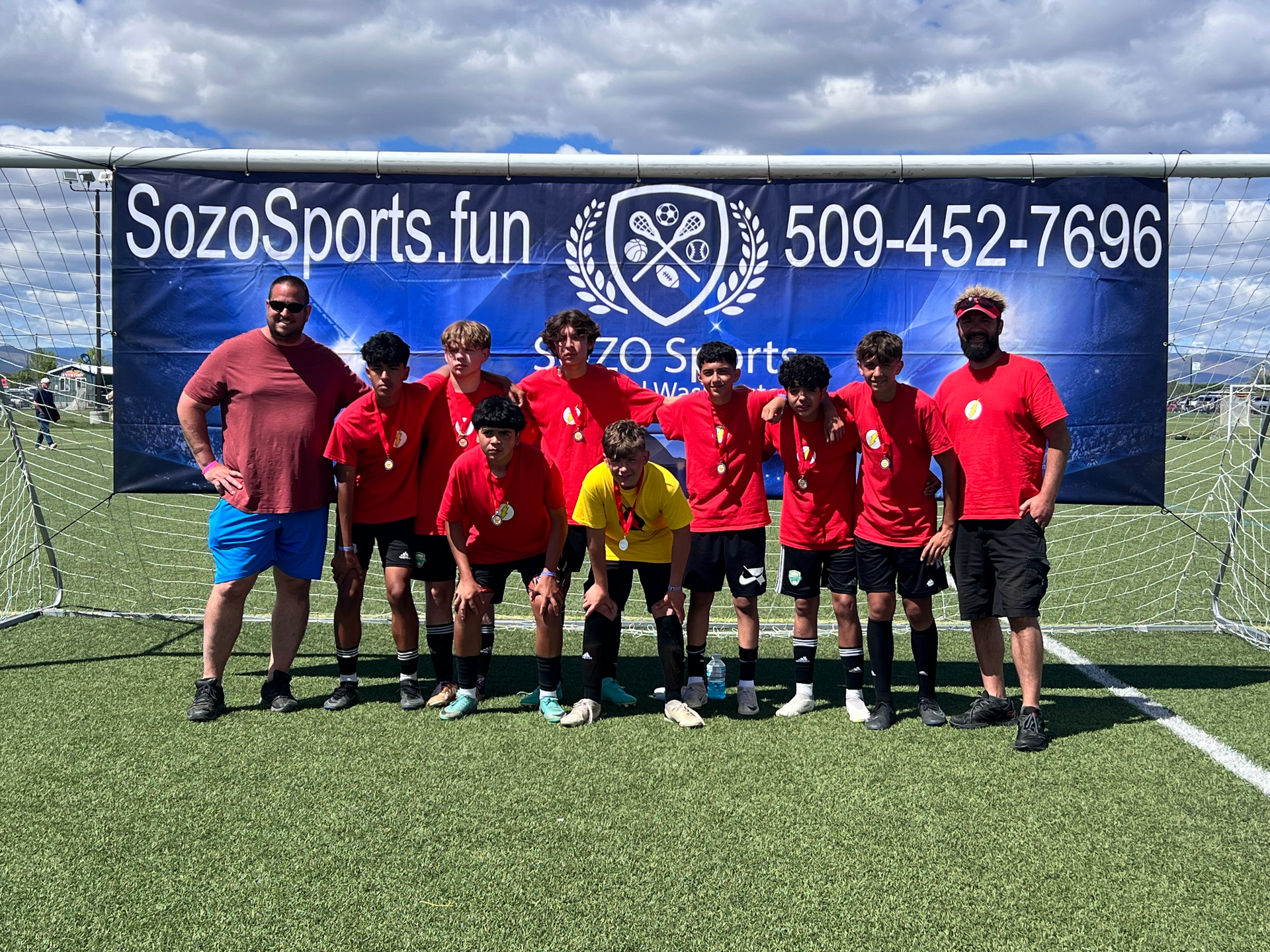 A group of young men are posing for a picture on a soccer field.