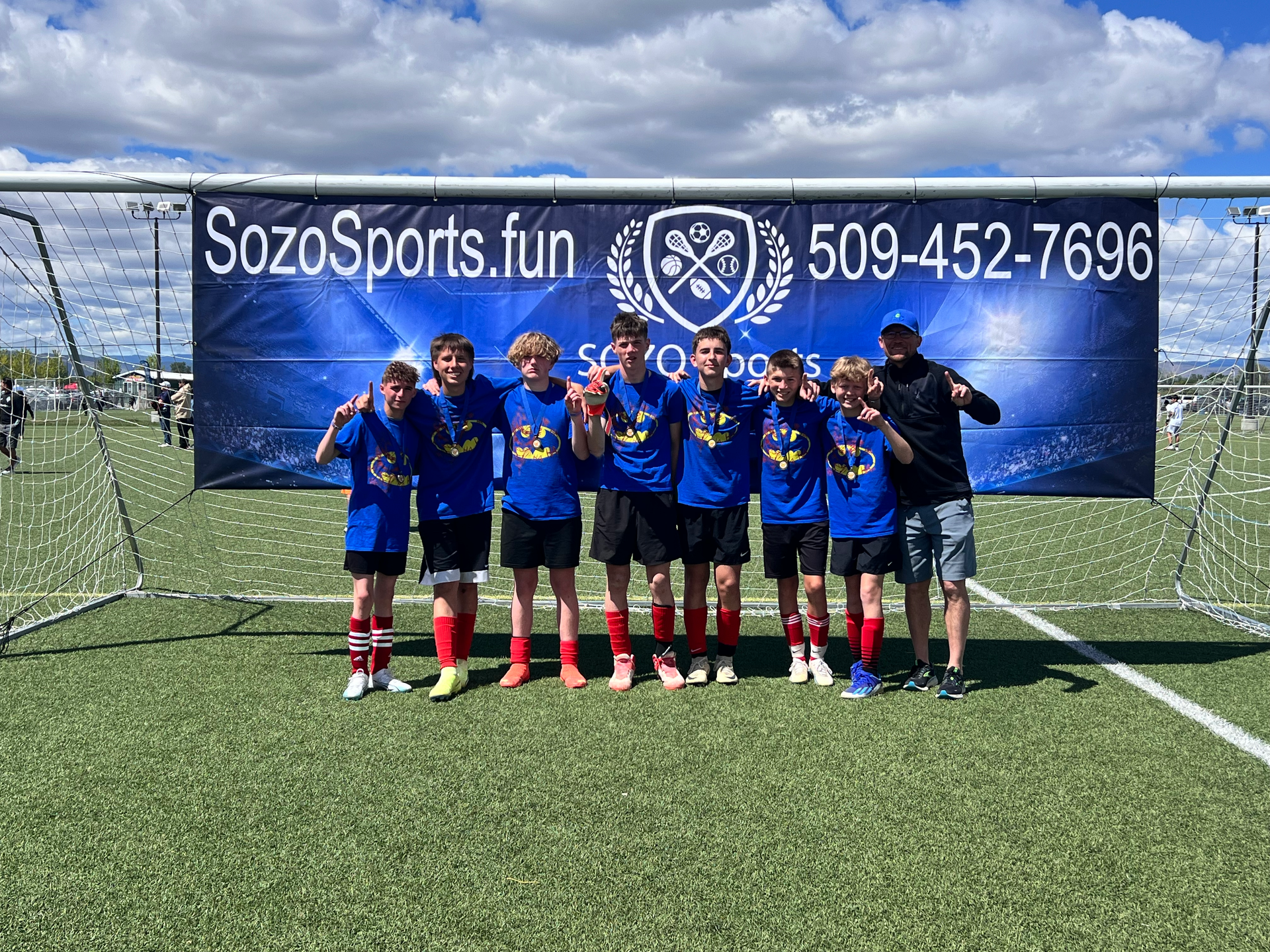 A group of boys are posing for a picture on a soccer field.