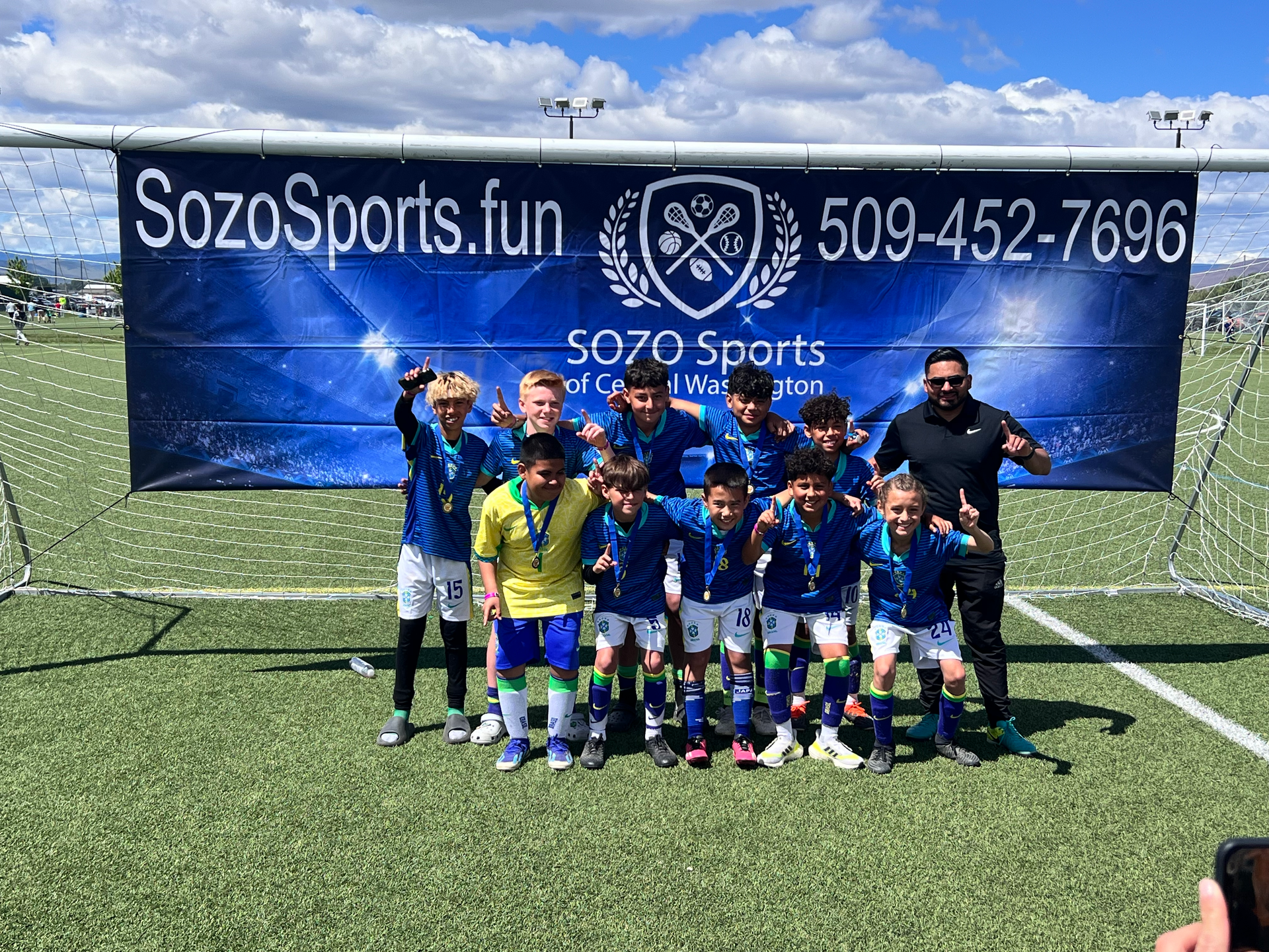 A group of young boys are posing for a picture on a soccer field.