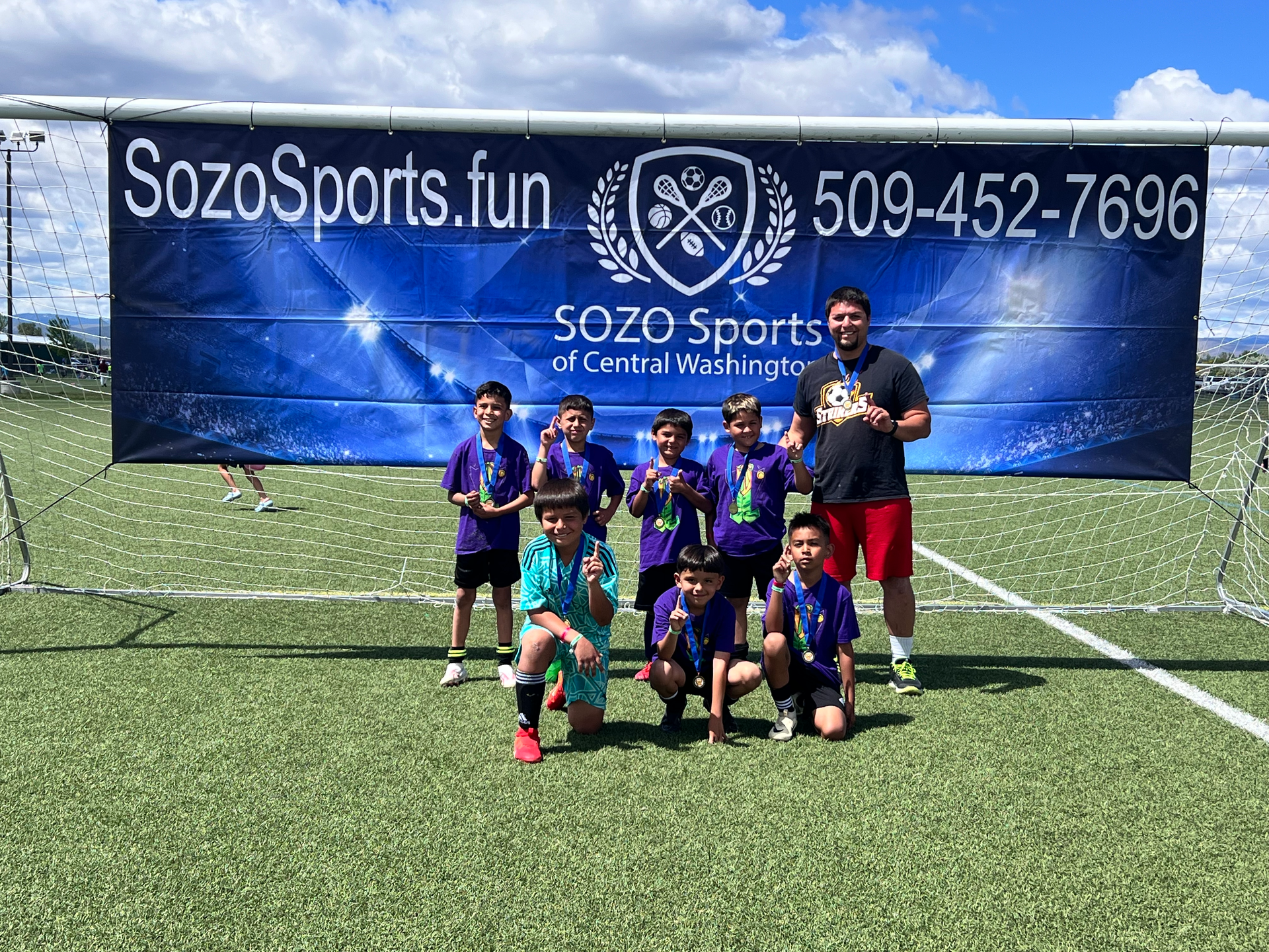 A group of young boys are posing for a picture on a soccer field.