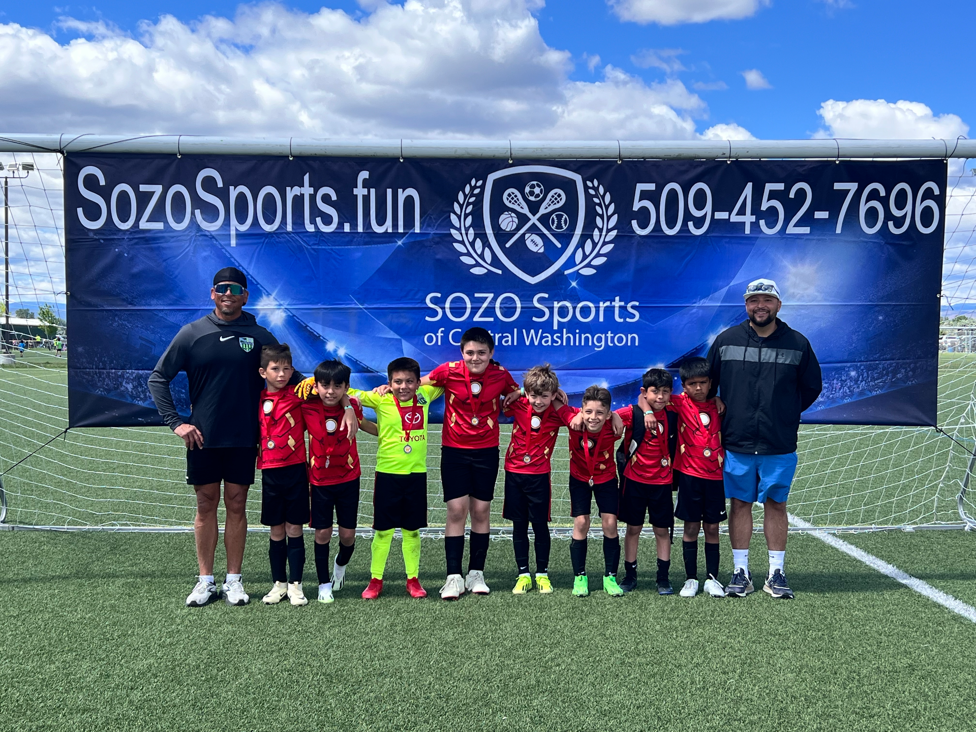 A group of young boys are posing for a picture on a soccer field.