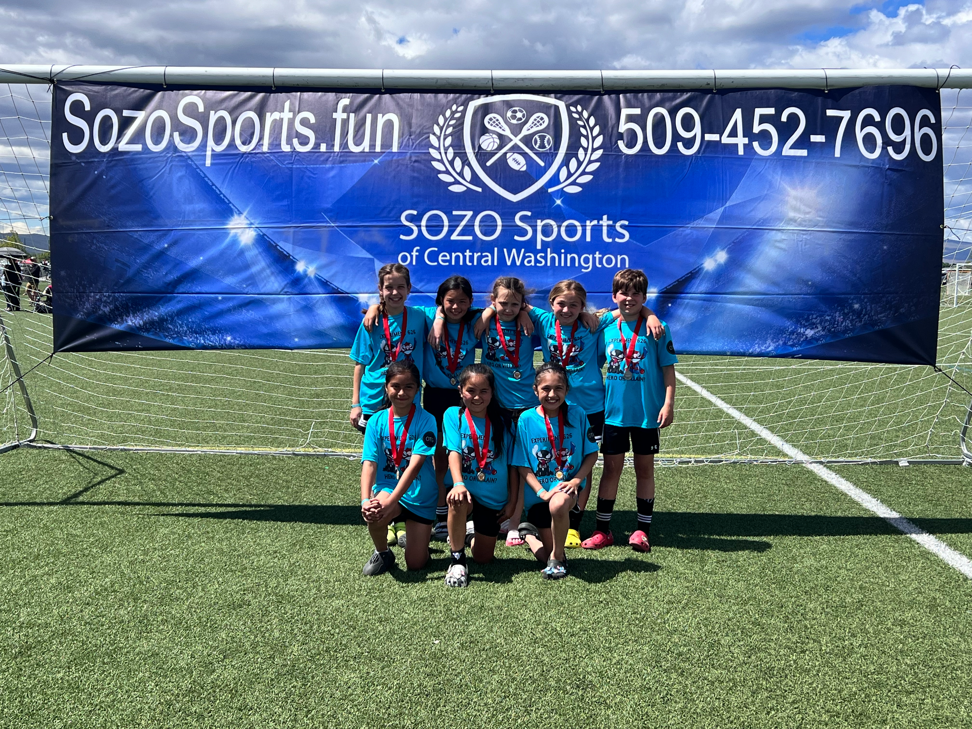 A group of young kids are posing for a picture on a soccer field.