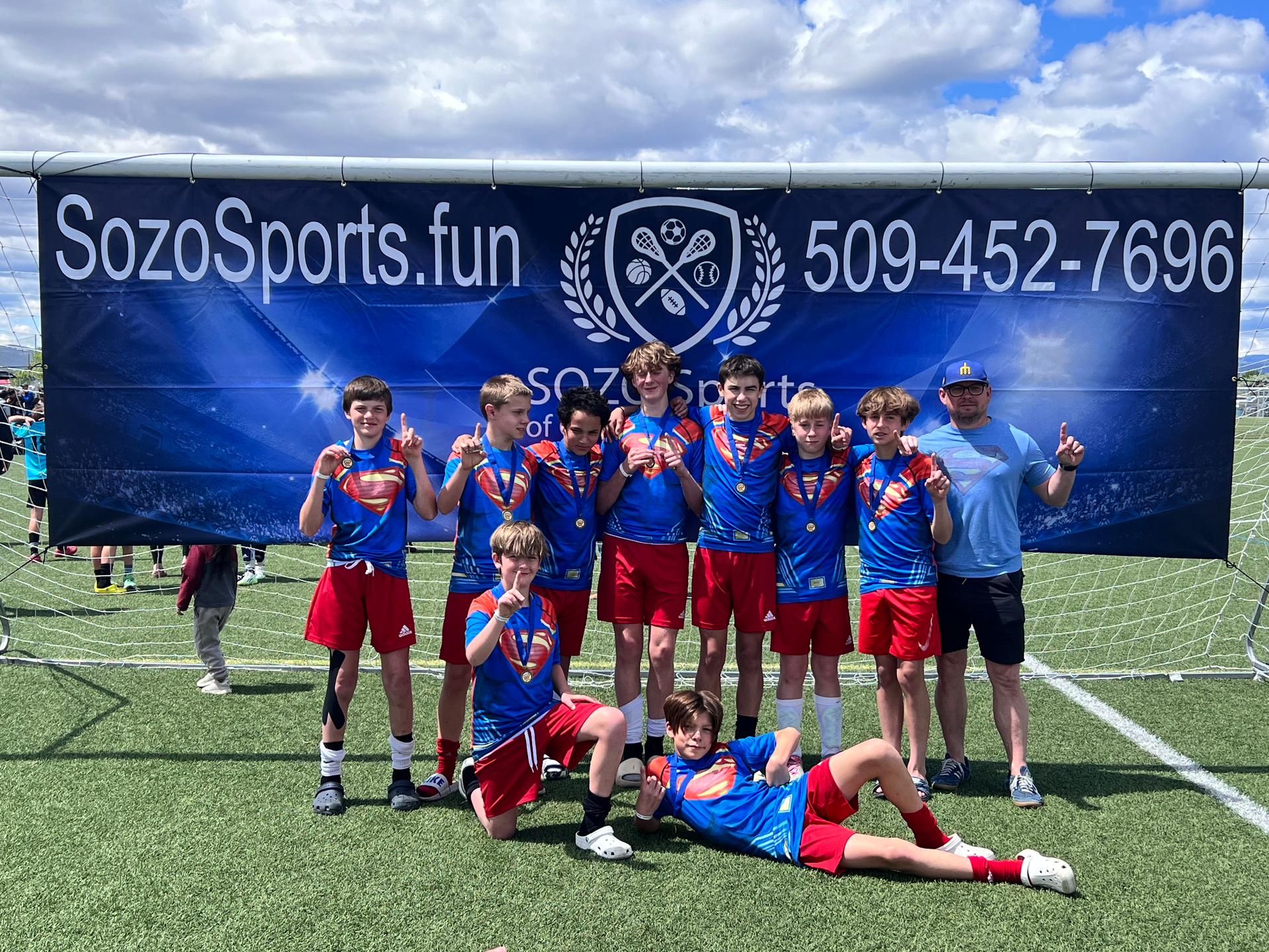 A group of young boys are posing for a picture on a soccer field.