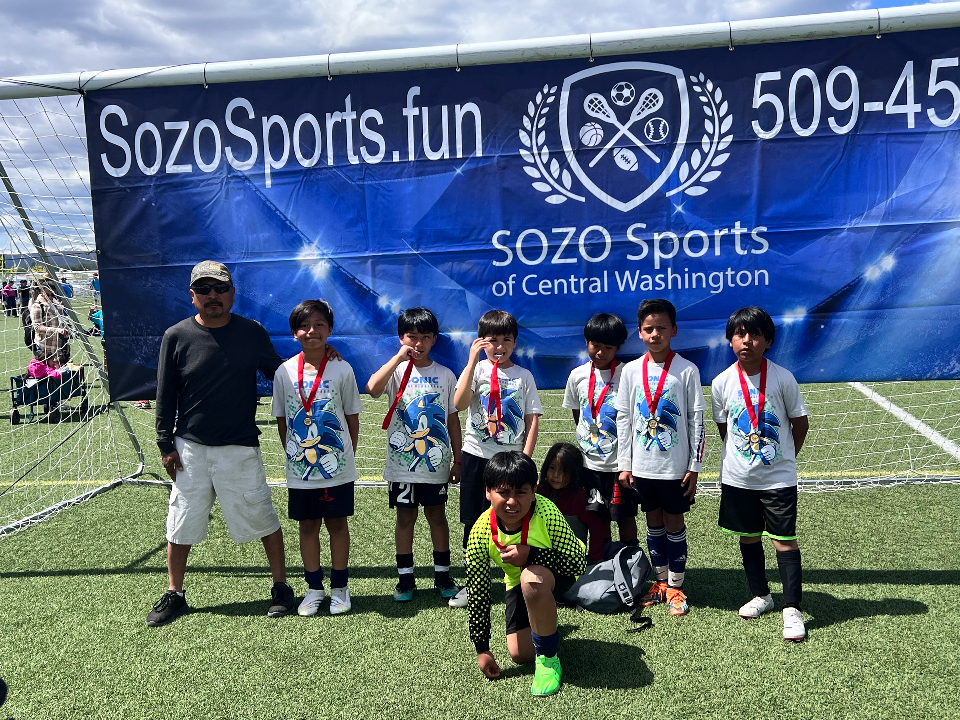 A group of young boys are posing for a picture on a soccer field.