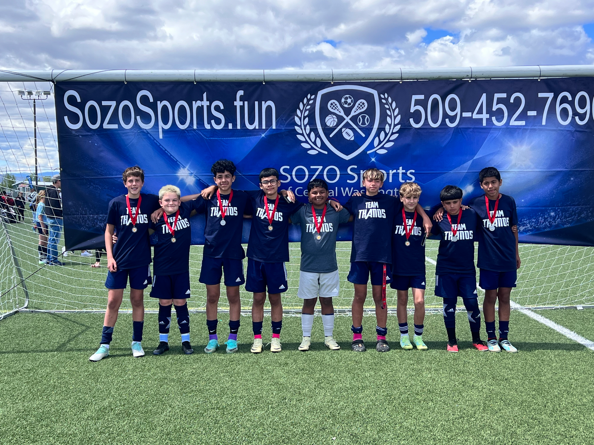 A group of young boys are posing for a picture on a soccer field.