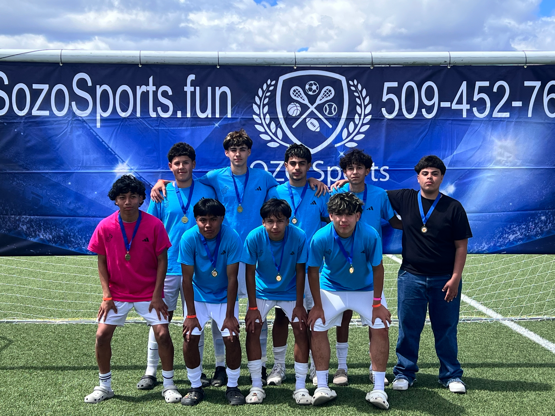 A group of young men are posing for a picture on a soccer field.