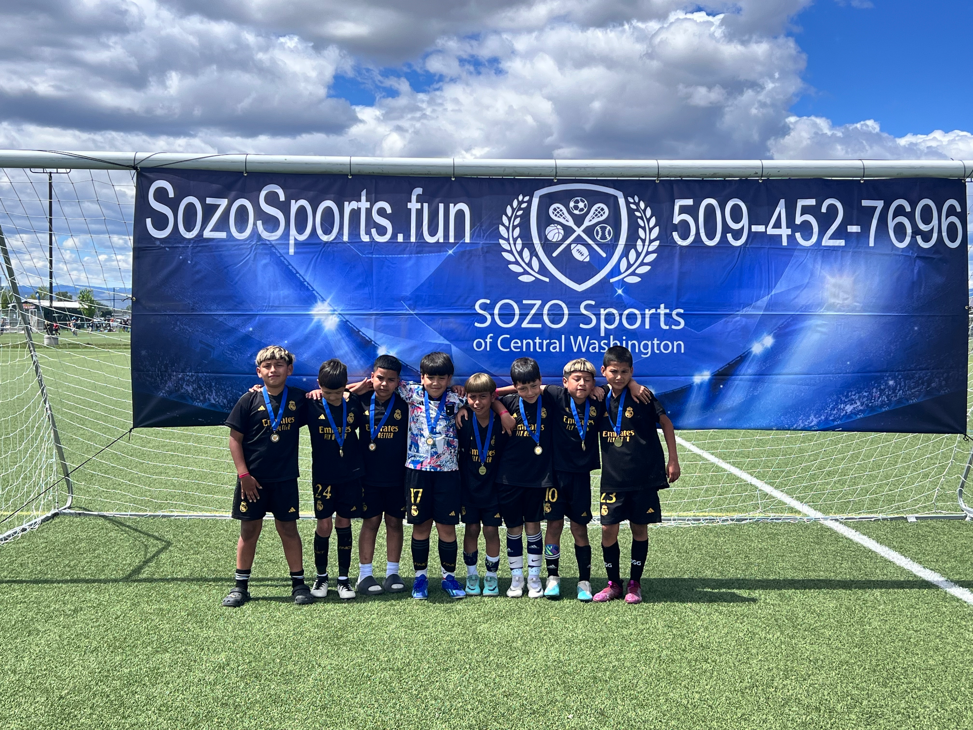 A group of young boys are posing for a picture on a soccer field.