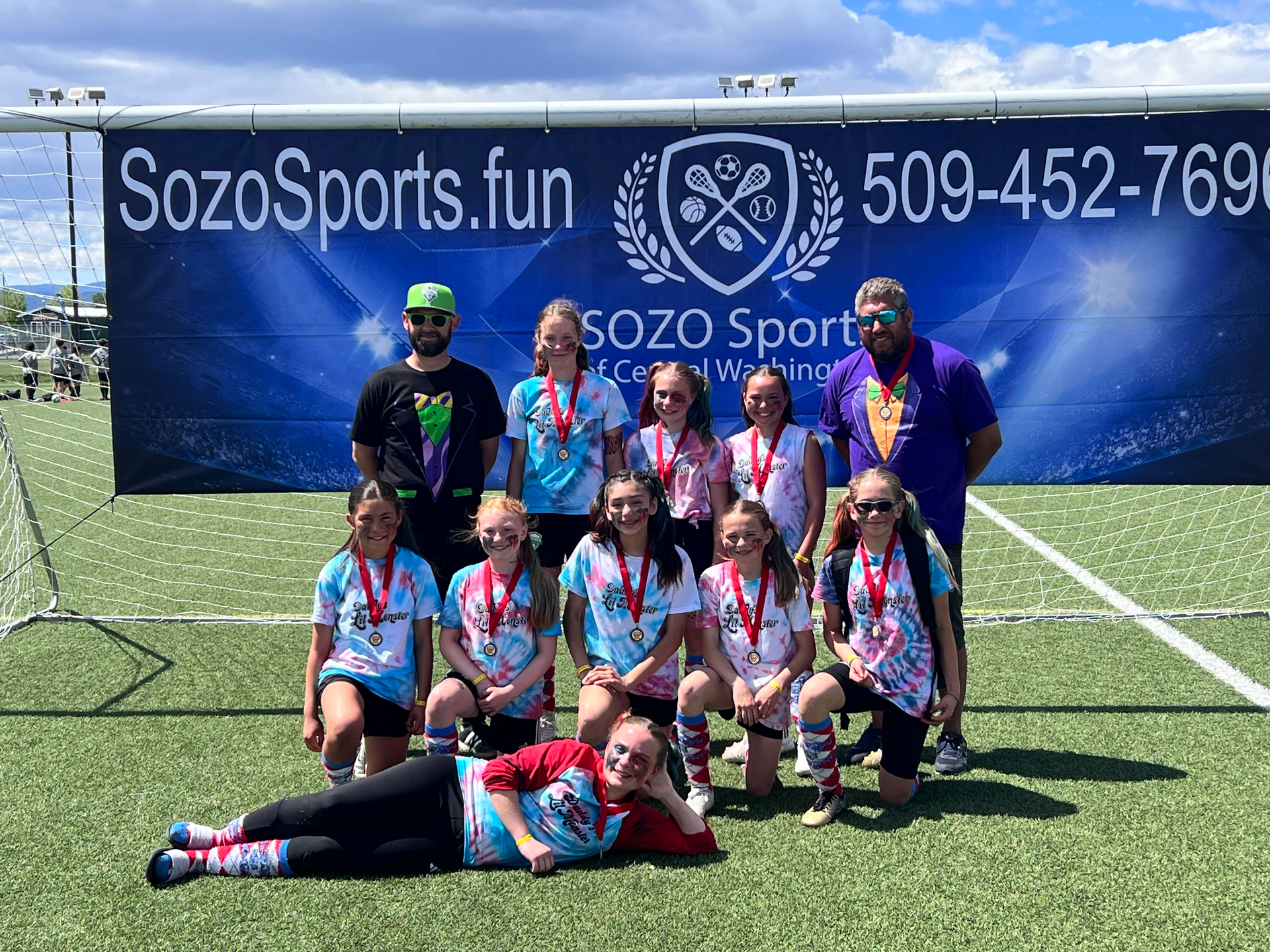 A group of young girls are posing for a picture on a soccer field.