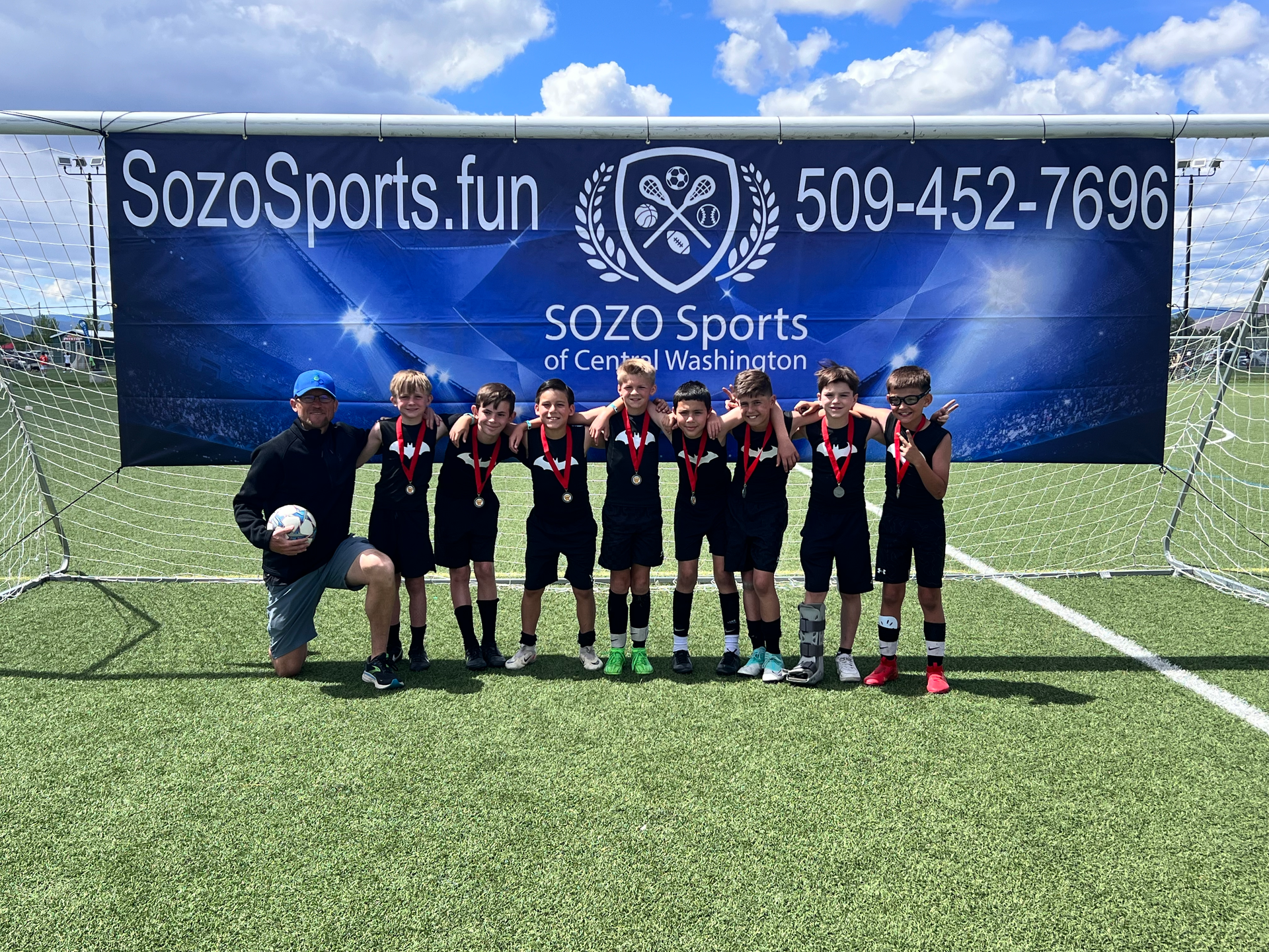 A group of young boys are posing for a picture on a soccer field.