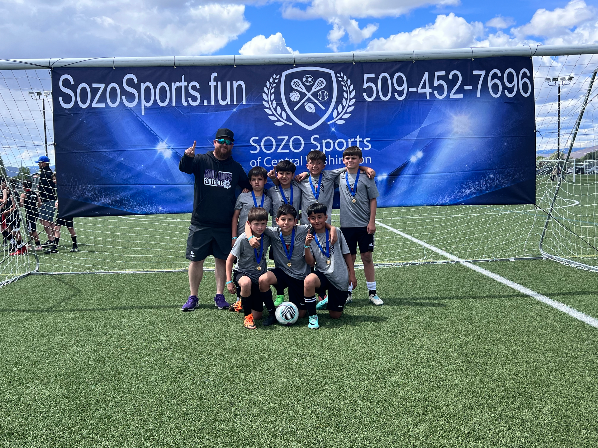 A group of young boys are posing for a picture on a soccer field.