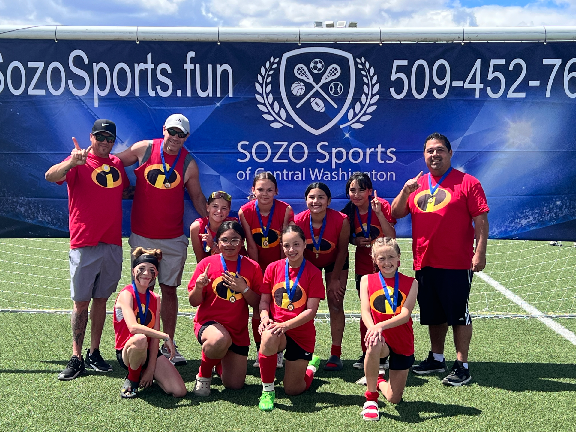 A group of people are posing for a picture on a soccer field.