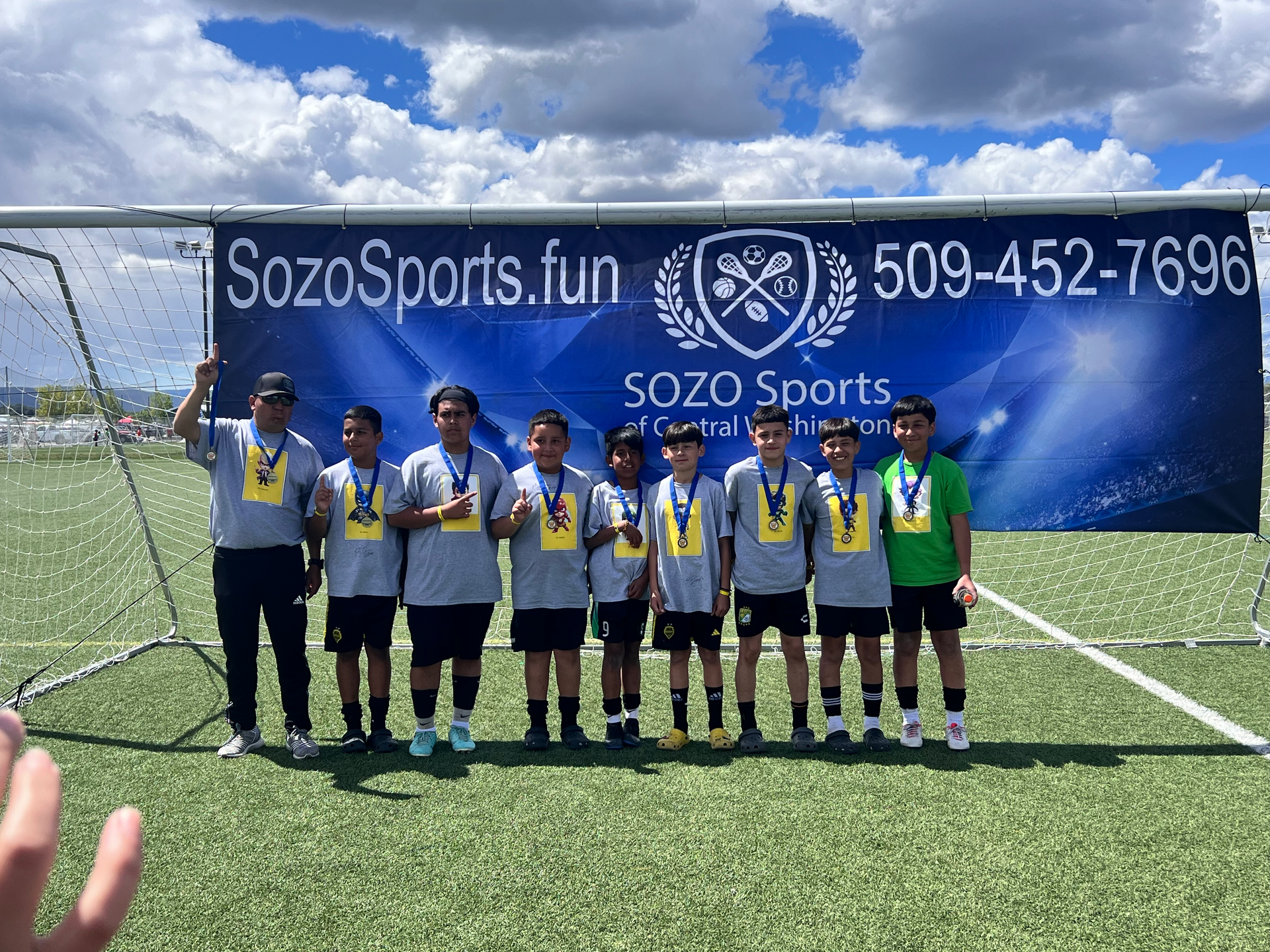 A group of young boys are posing for a picture on a soccer field.