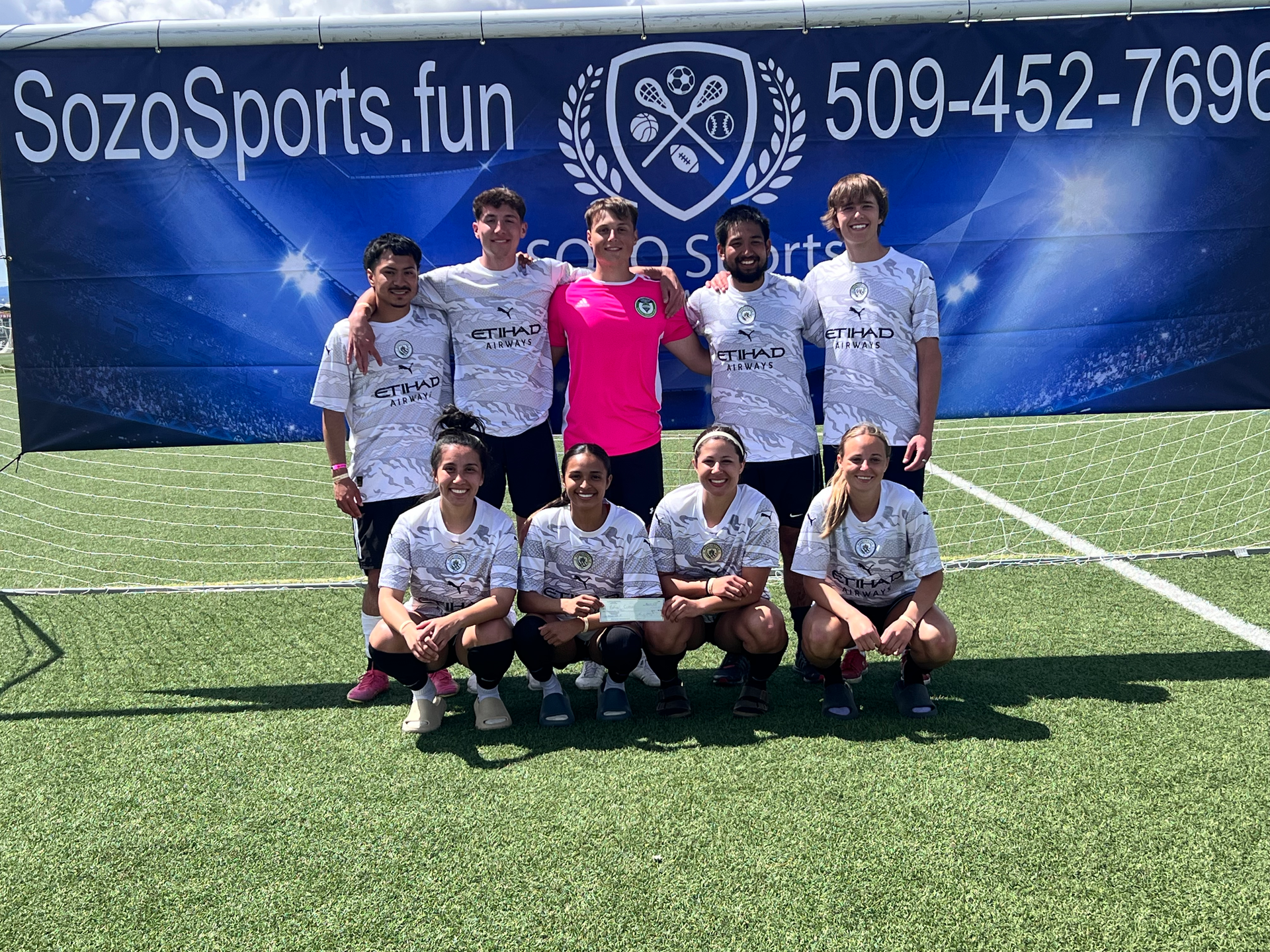 A group of people are posing for a picture on a soccer field.