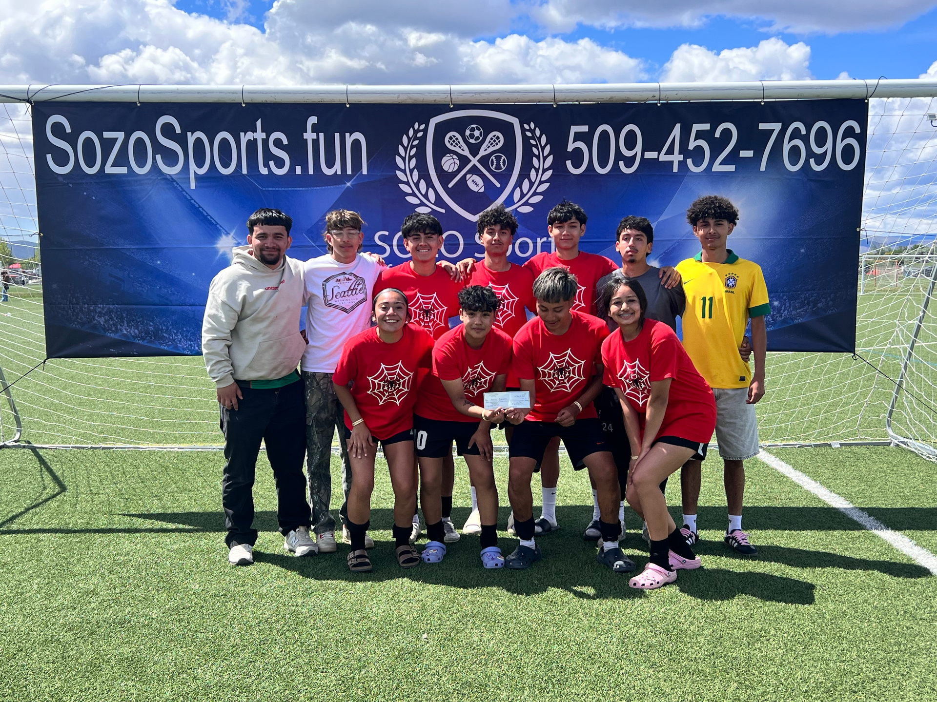 A group of young people are posing for a picture on a soccer field.