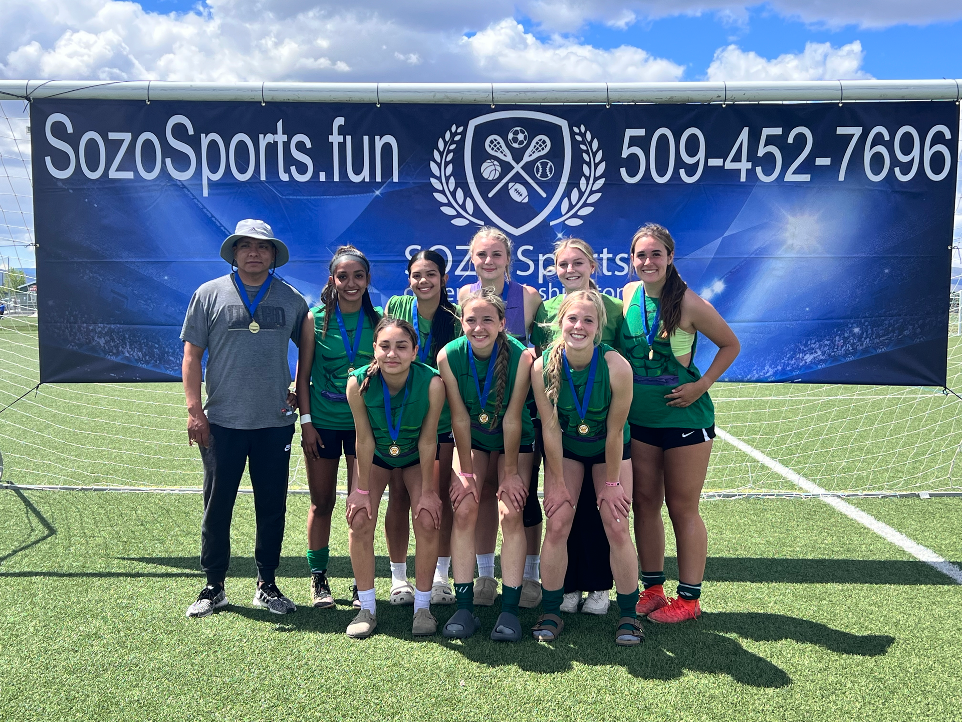 A group of young girls are posing for a picture on a field.
