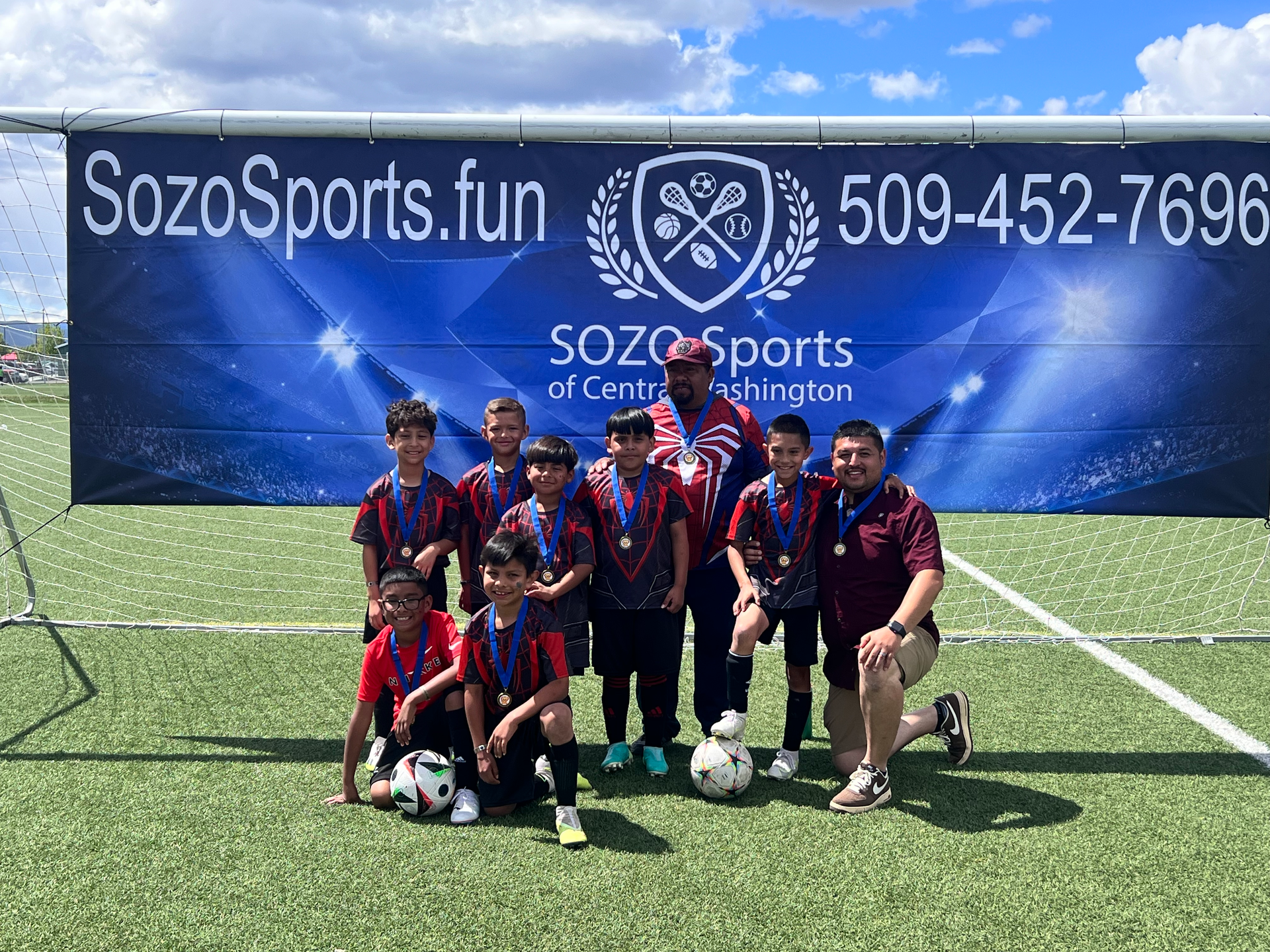 A group of young boys are posing for a picture on a soccer field.