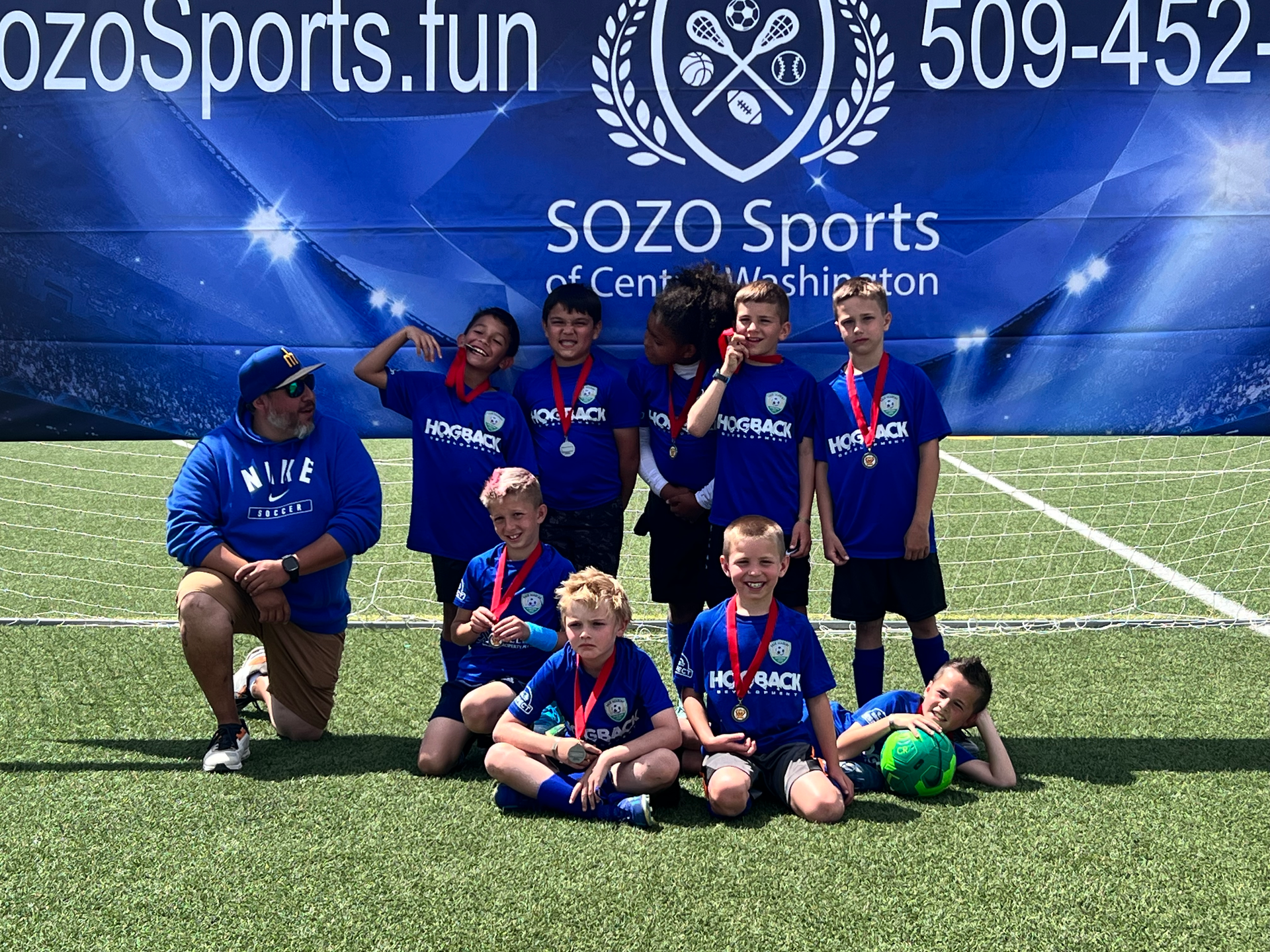 A group of young boys are posing for a picture on a soccer field.