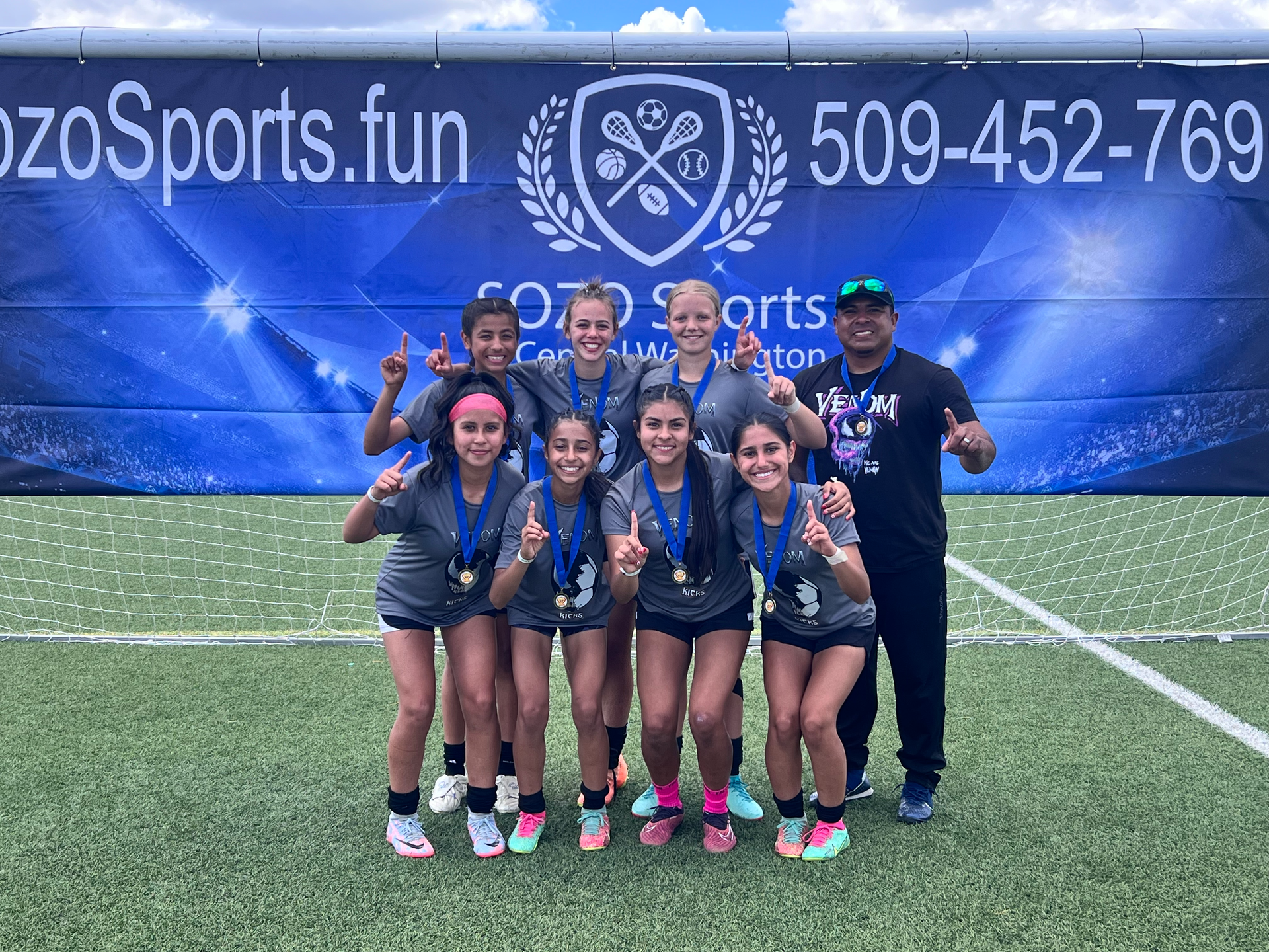 A group of young girls are posing for a picture on a soccer field.