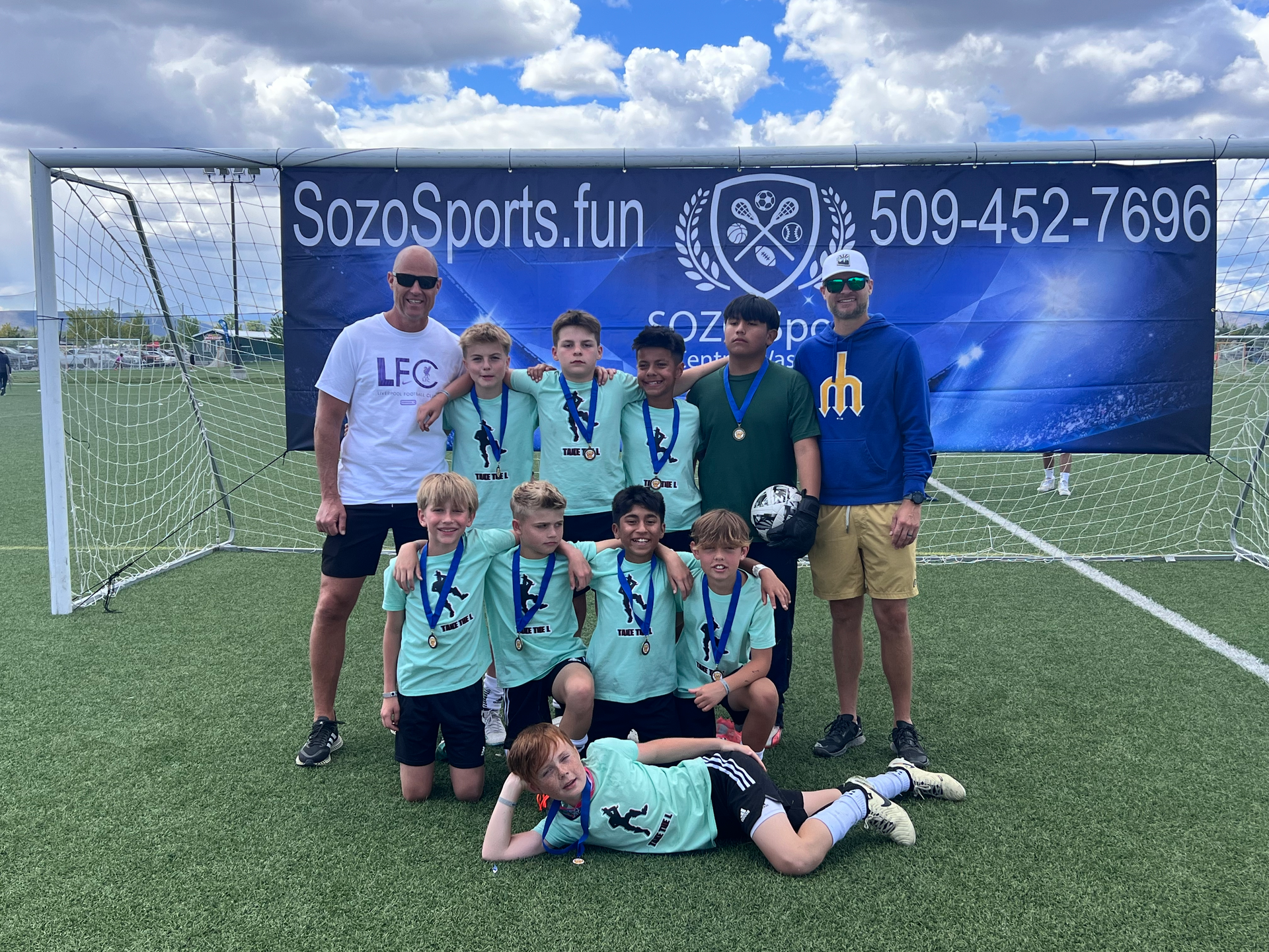 A group of young boys are posing for a picture on a soccer field.