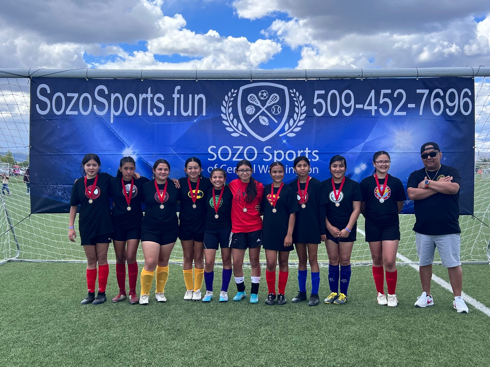 A group of young girls are posing for a picture on a soccer field.