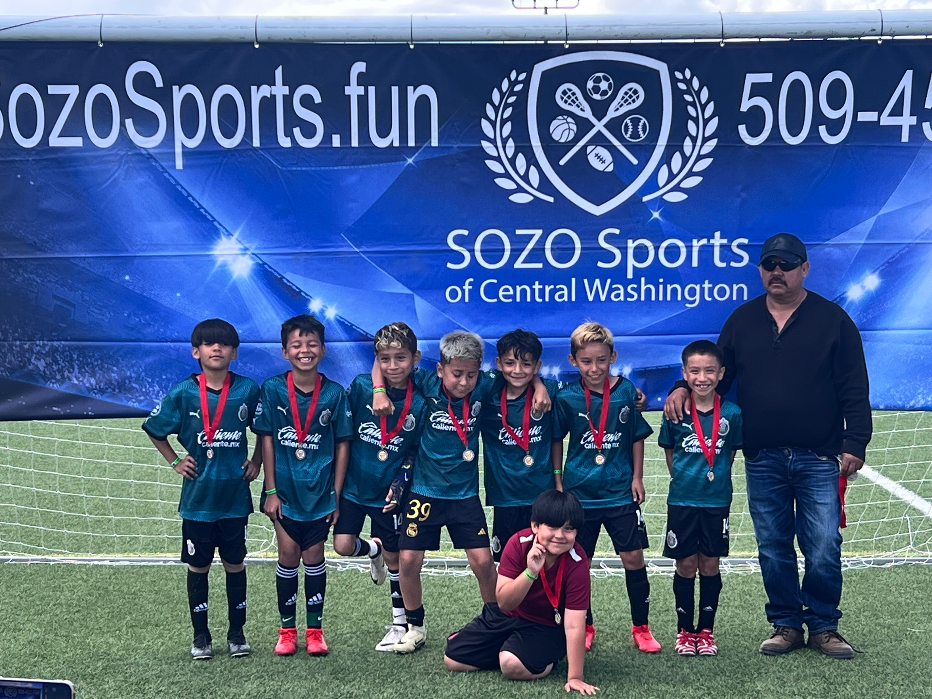 A group of young boys are posing for a picture on a soccer field.