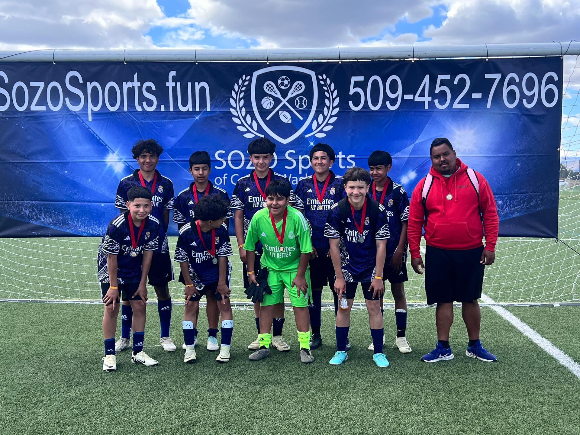 A group of young boys are posing for a picture on a soccer field.
