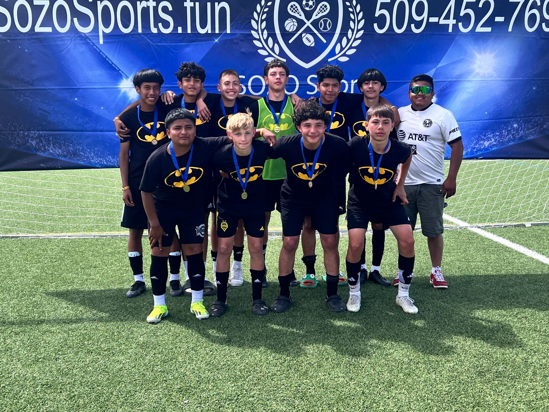 A group of young boys are posing for a picture on a soccer field.