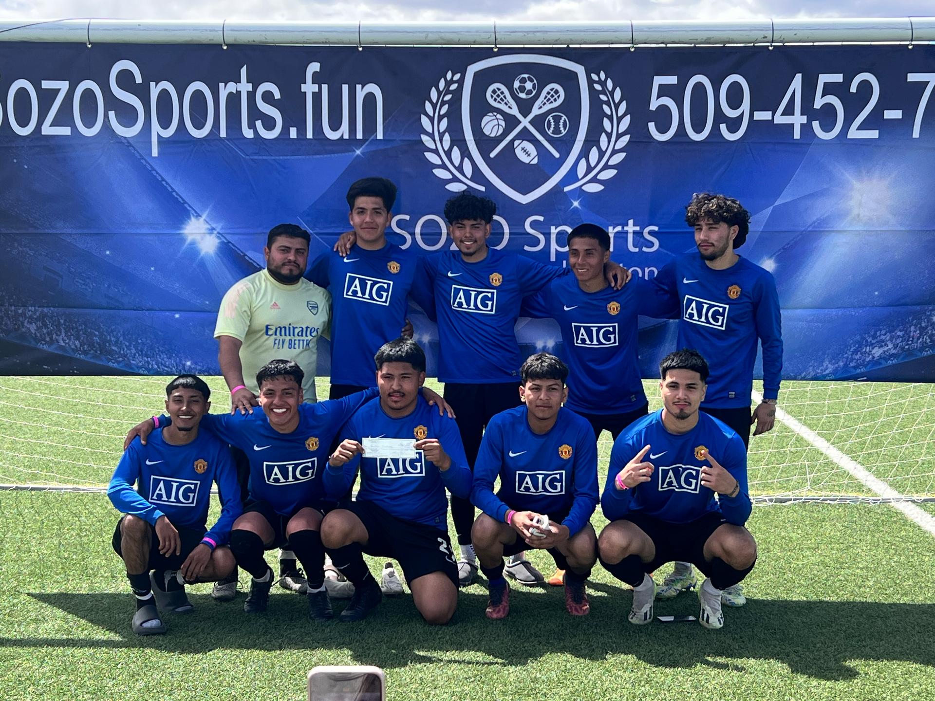 A group of soccer players are posing for a picture on a field.