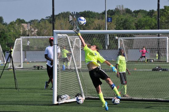 A soccer goalie is jumping in the air to catch a soccer ball.