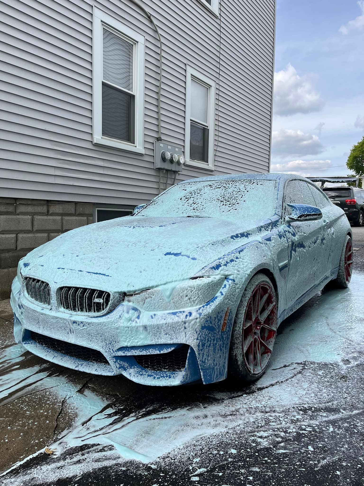 A car covered in foam is parked in front of a house.