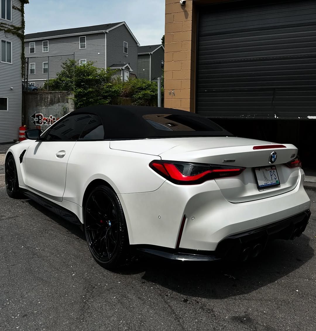 A white convertible is parked in front of a garage