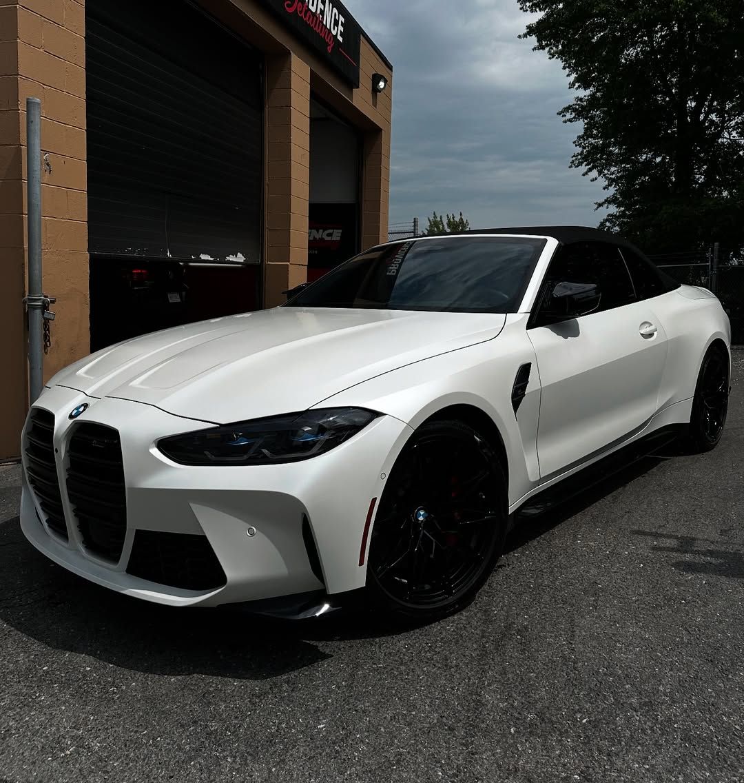 A white bmw is parked in front of a garage